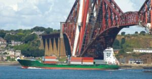 (freight ship passing under a bridge)